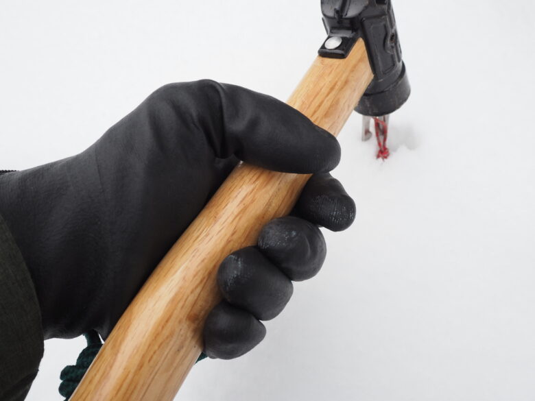 ワークマンの防寒防水手袋を着用して、雪上でペグハンマーを握っている様子