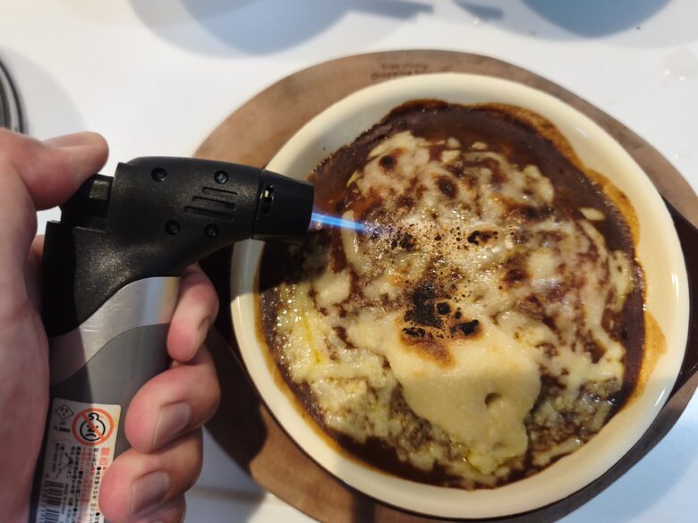 ダイソーコンパクトガスバーナーでチーズドリアを炙っている状況の接写